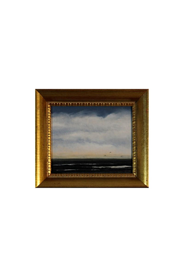 Framed painting of a seascape with a gold frame on a white background